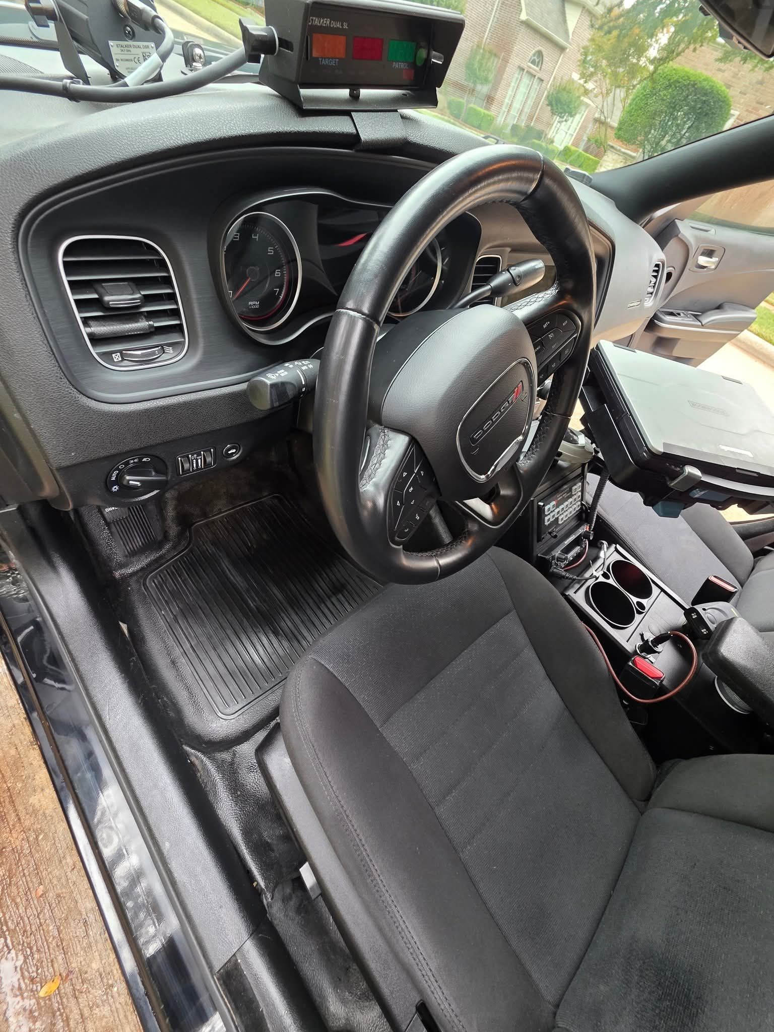 Person steam-cleans a gray car seat with a handheld upholstery tool.