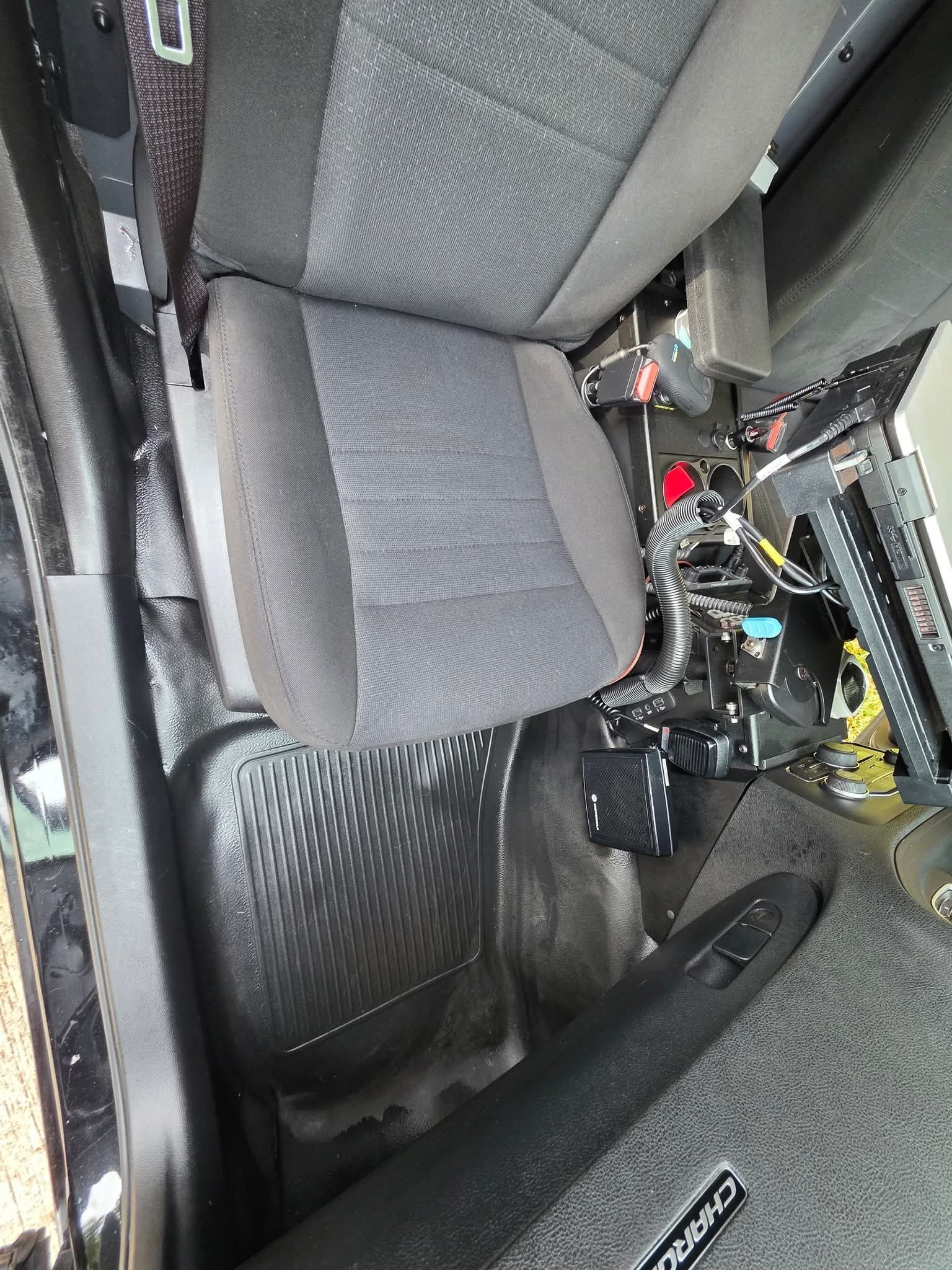 Interior of a car with a gray seat and carbon-fiber trim near exposed mechanical parts