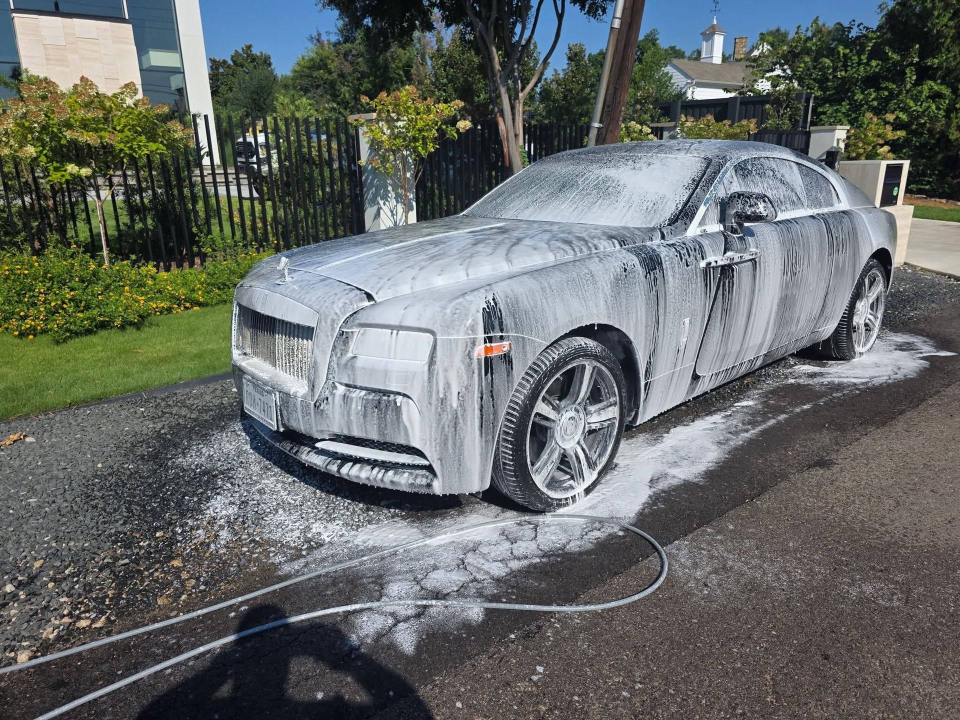White car covered in foam during a driveway wash outdoors