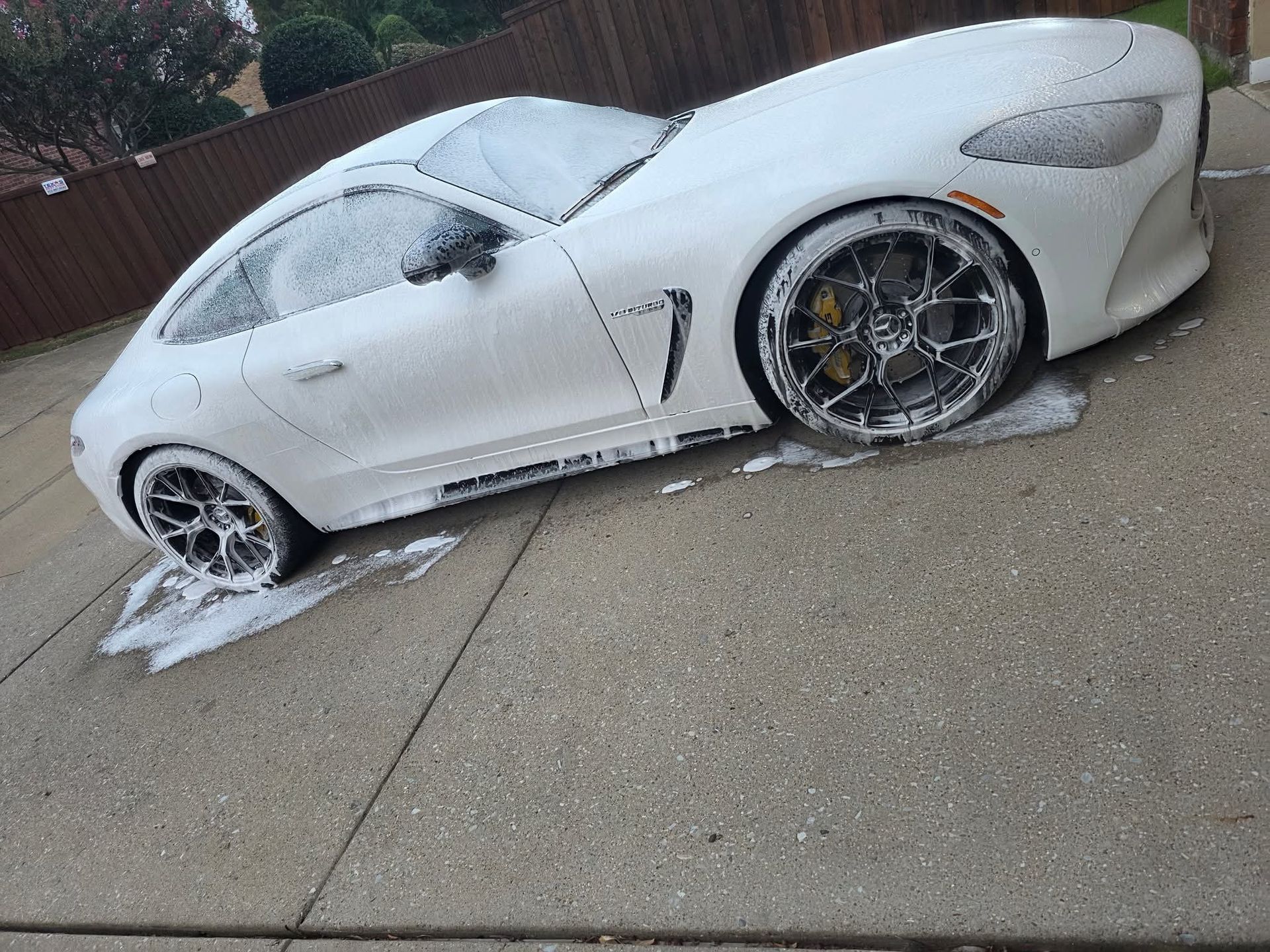White sports car covered in snow, parked on a driveway in winter.