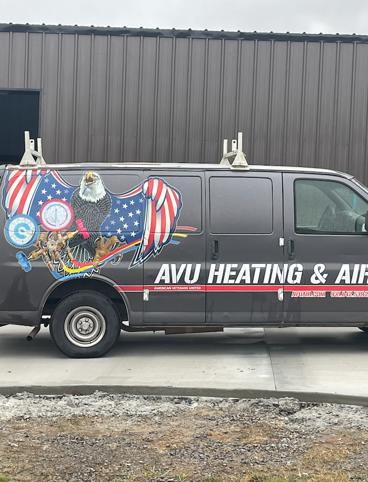A black van with an american flag on the side is parked in front of a building.