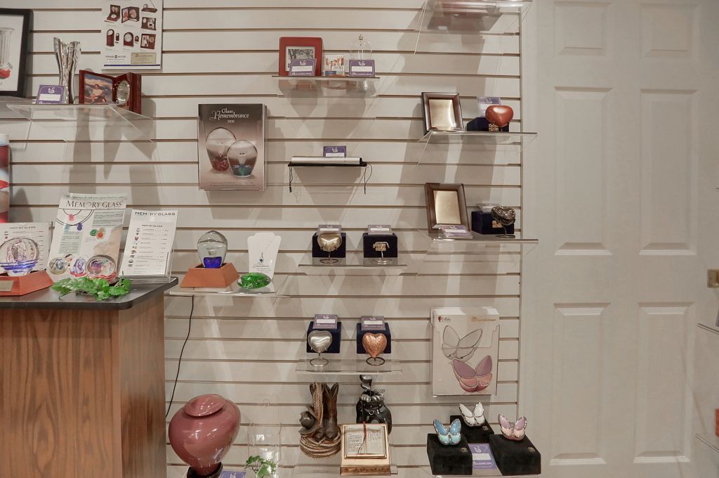 Wall display of small decorative items and framed art in a shop, with a door on the right.