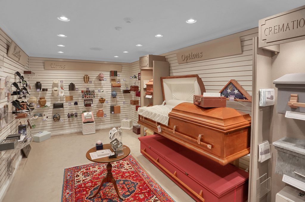 Bright retail store interior with handbags, accessories, and a display of orange and red caskets