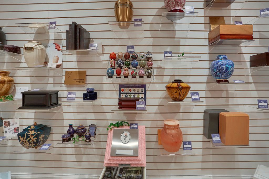 Display of assorted colorful wall hangings and small decor items arranged on a slatted store wall.