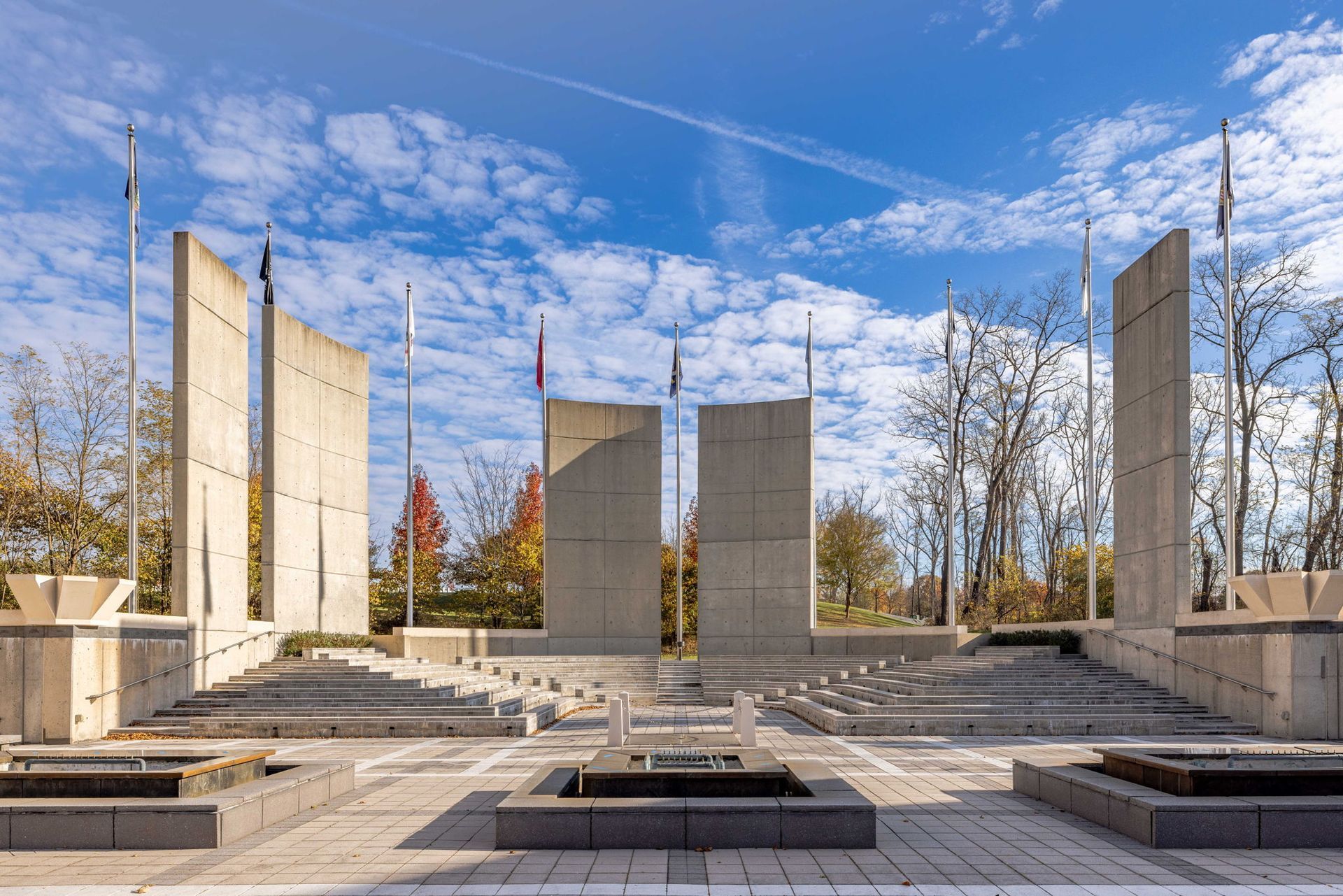 Modern outdoor memorial with tall stone slabs and benches under a bright blue sky