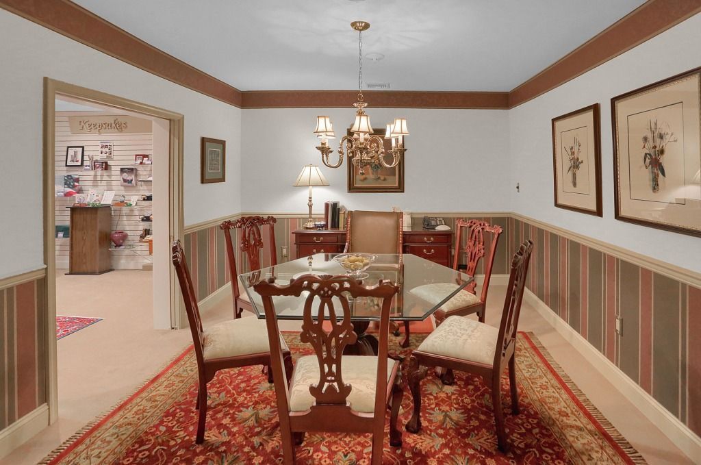 Formal room with chandelier, round table, red patterned rug, and striped walls