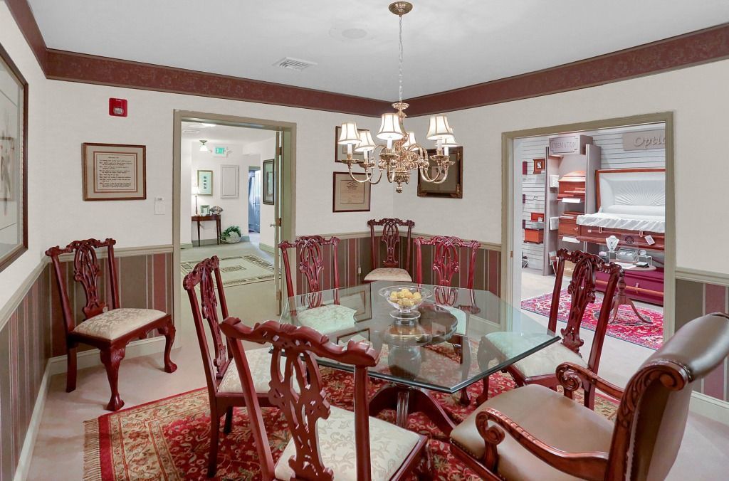 Elegant room with glass table, red chairs, chandelier, and open doorway to kitchen