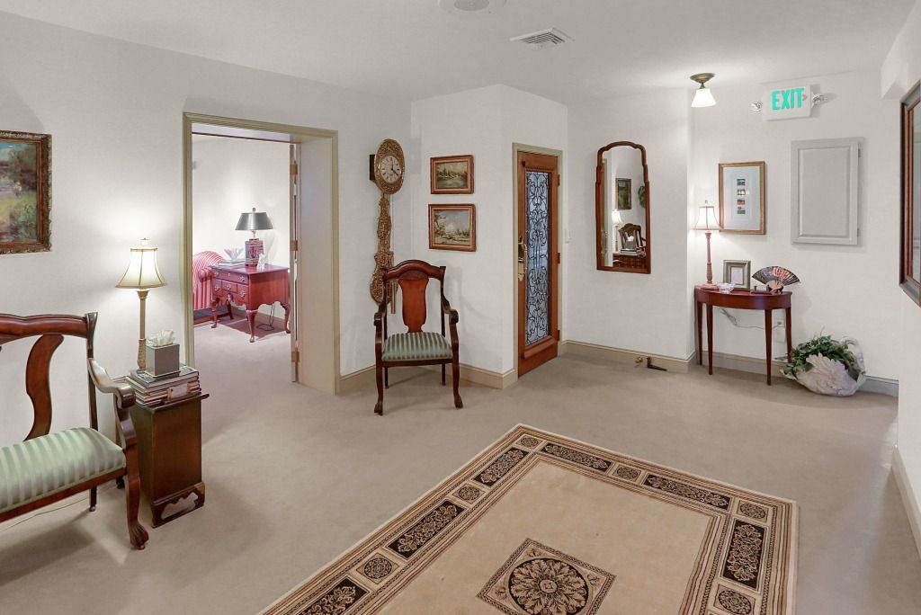 Bright room with cream carpet, wooden furniture, wall mirrors, and red accents behind a doorway