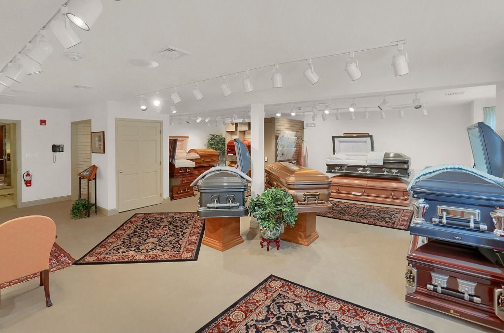 Bright showroom with upholstered chairs, patterned rugs, and white walls under track lighting.