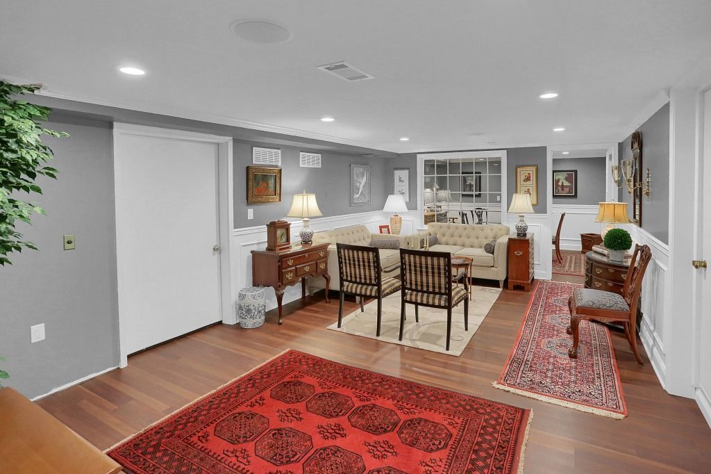 Modern open-concept living and dining room with red rugs, gray walls, and warm lighting