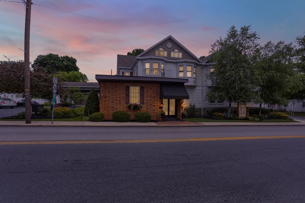 Dusk view of a lit building with a brick entrance and trees along a street.