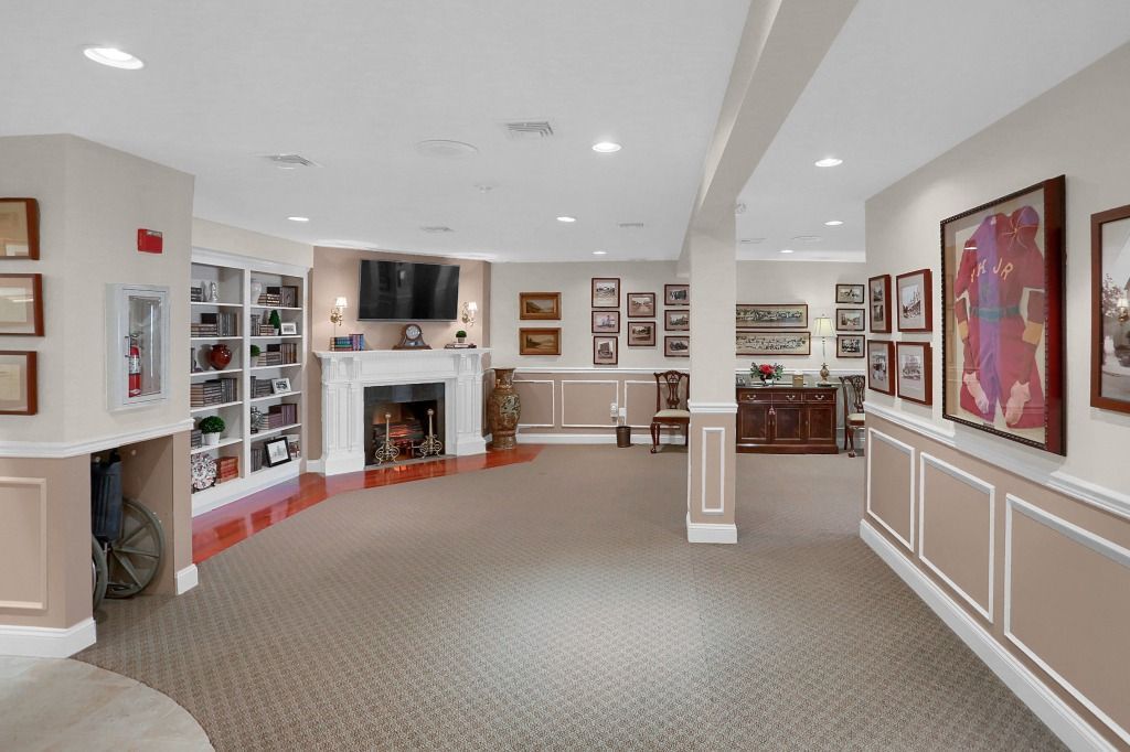 Bright showroom with fireplace, carpet, framed art, and white paneled walls