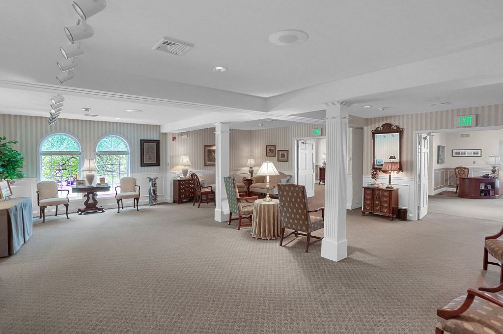 Spacious lobby with carpeted seating areas, white columns, and arched windows letting in green light