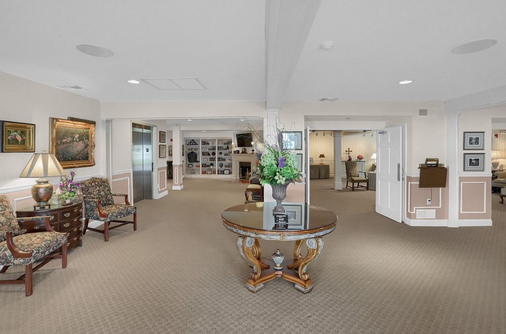 Spacious beige room with floral chairs, glass coffee table, and wall art in a bright home interior