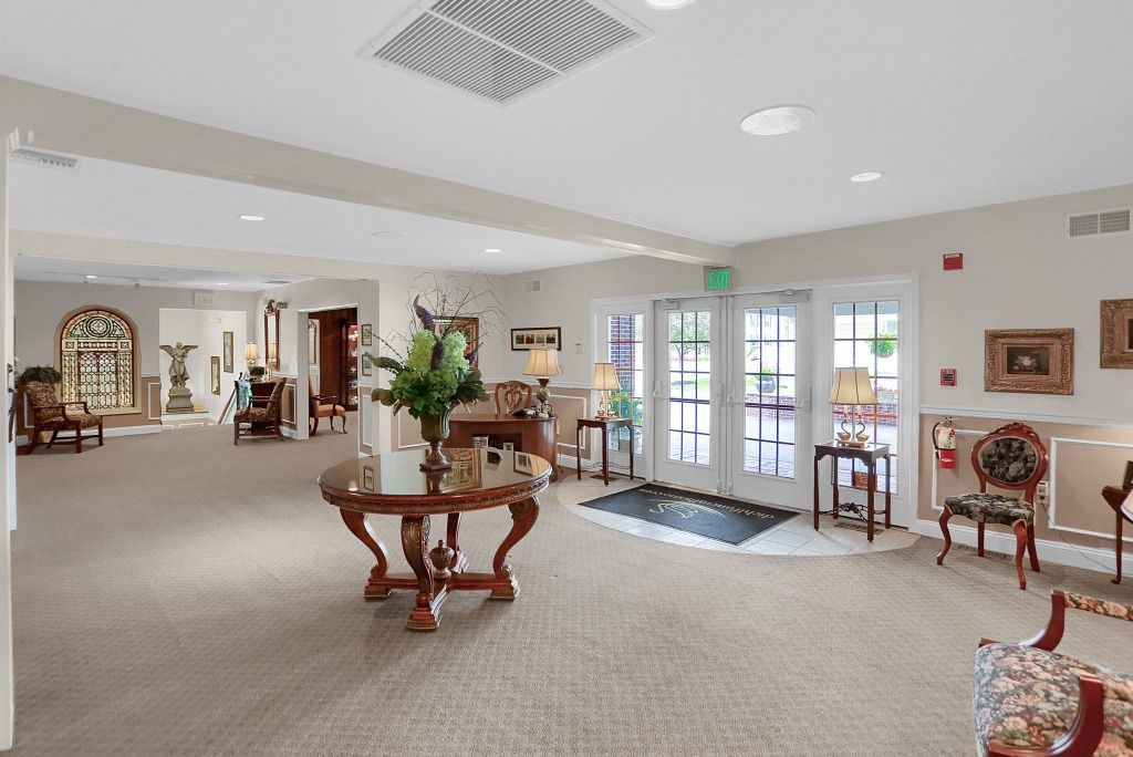 Spacious beige lobby with seating, round table, and glass doors leading outside