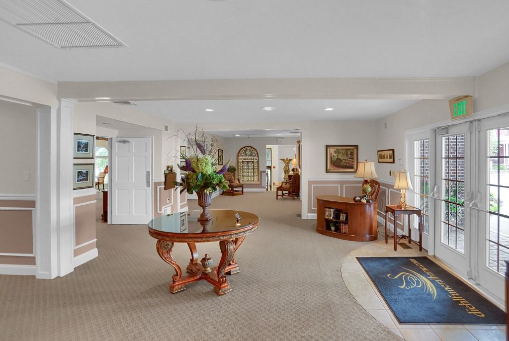 Bright, spacious lobby with carpet, wooden table, piano, and glass doors
