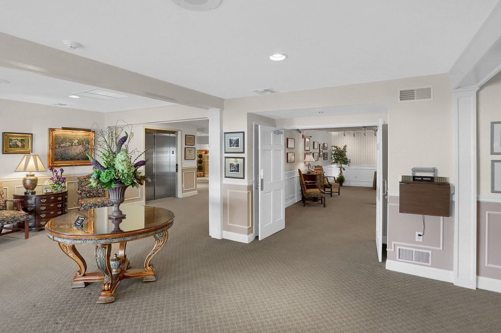 Elegant hotel lobby with carpeted seating areas, ornate tables, and framed artwork
