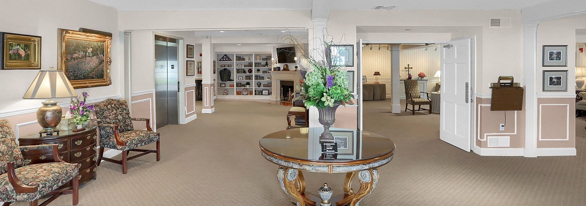 Elegant beige living room with floral sofa, glass coffee table, and white built-in shelves.