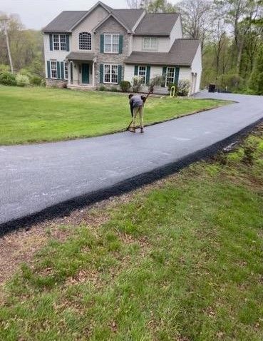 Person pressure-washing a curved driveway in front of a suburban house