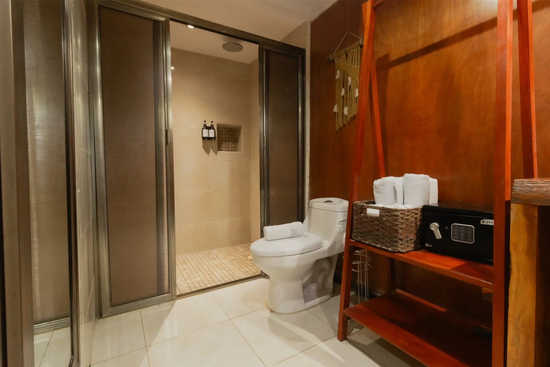 Baño moderno con ducha de cristal, inodoro, suelo de baldosas y encimera de madera.