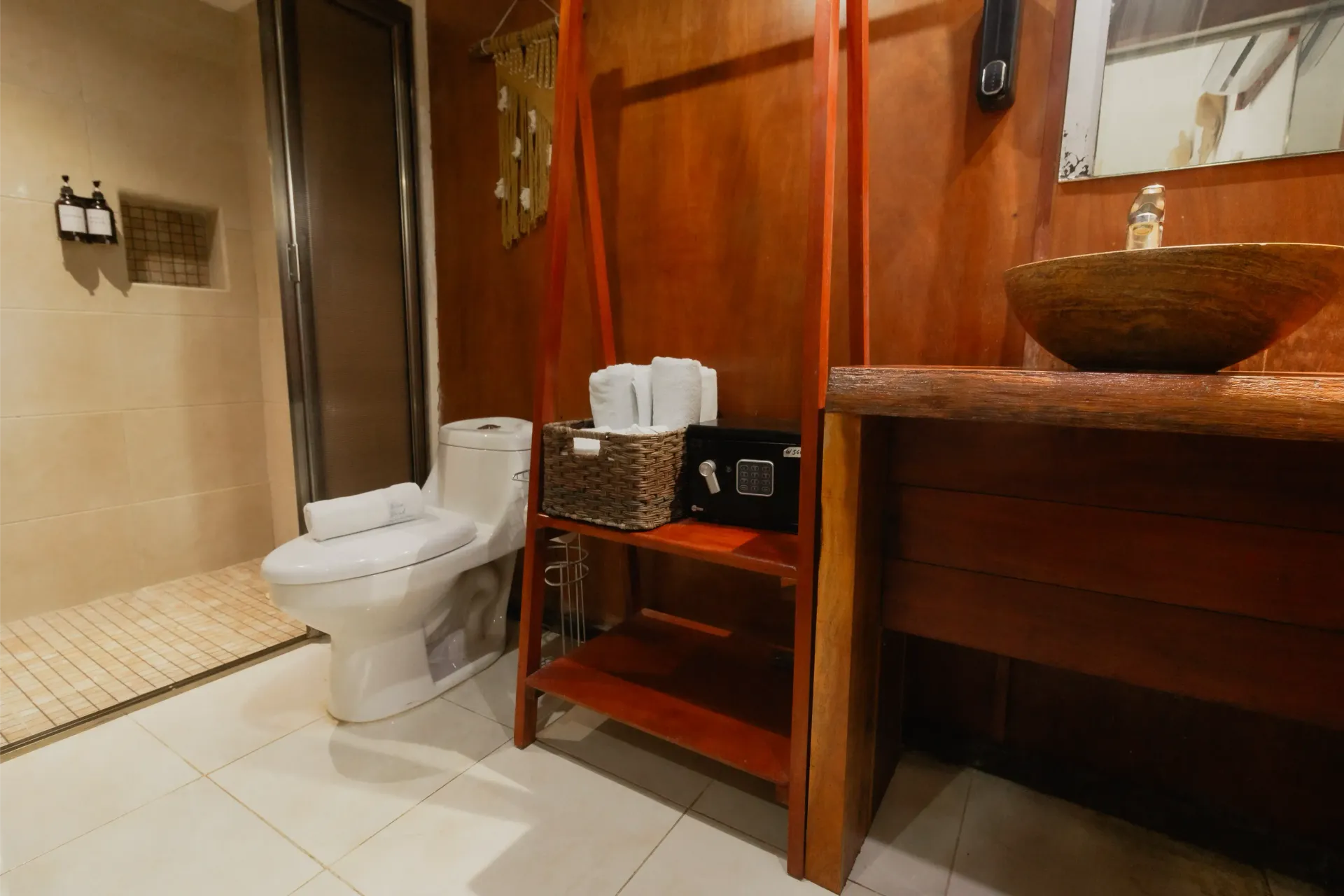 Baño pequeño con inodoro, tocador de madera, lavabo de mimbre y paredes alicatadas.