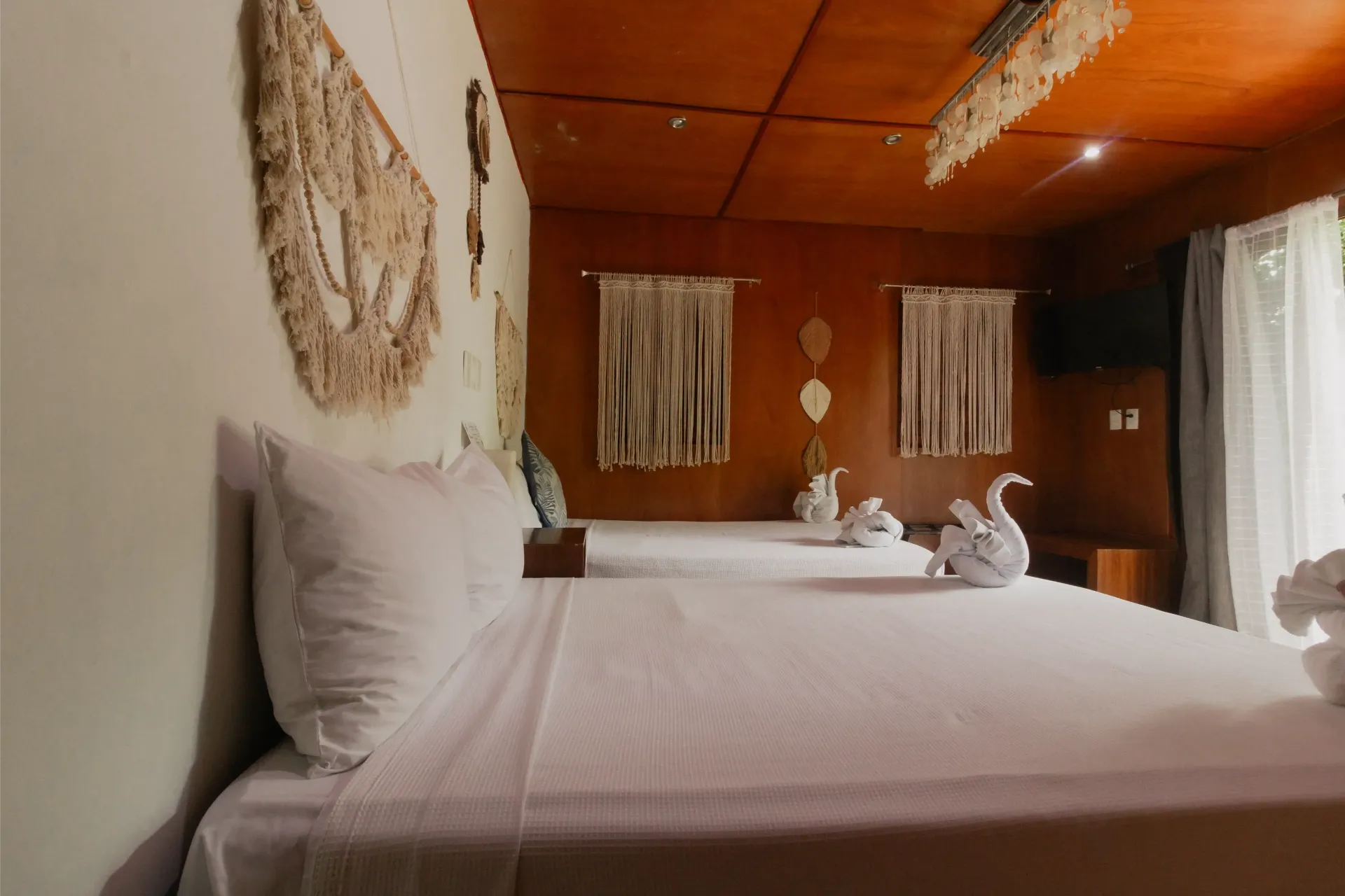 Acogedor dormitorio con cama blanca, decoración de pared tejida y paredes revestidas de cálidos paneles de madera.