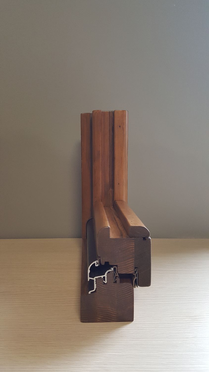 Sezione trasversale di un telaio di finestra in legno tinto, con un pezzo di alluminio attaccato.