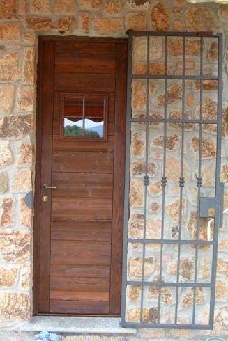 Porta in legno con cancelletto di sicurezza in ferro, incastonata nel muro di pietra.