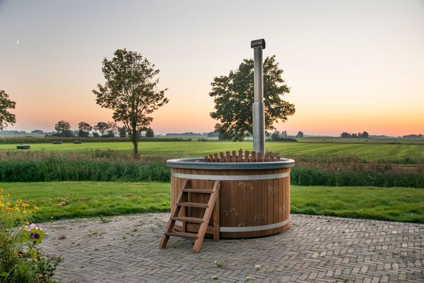 Een houten hottub staat midden in een veld.