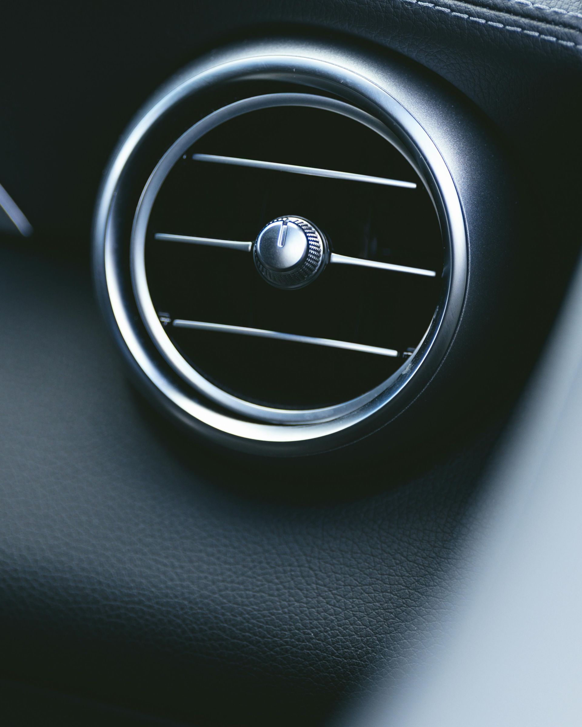 Close-up of a car dashboard air vent with silver trim on a black interior panel. ac repair or heat repair.
