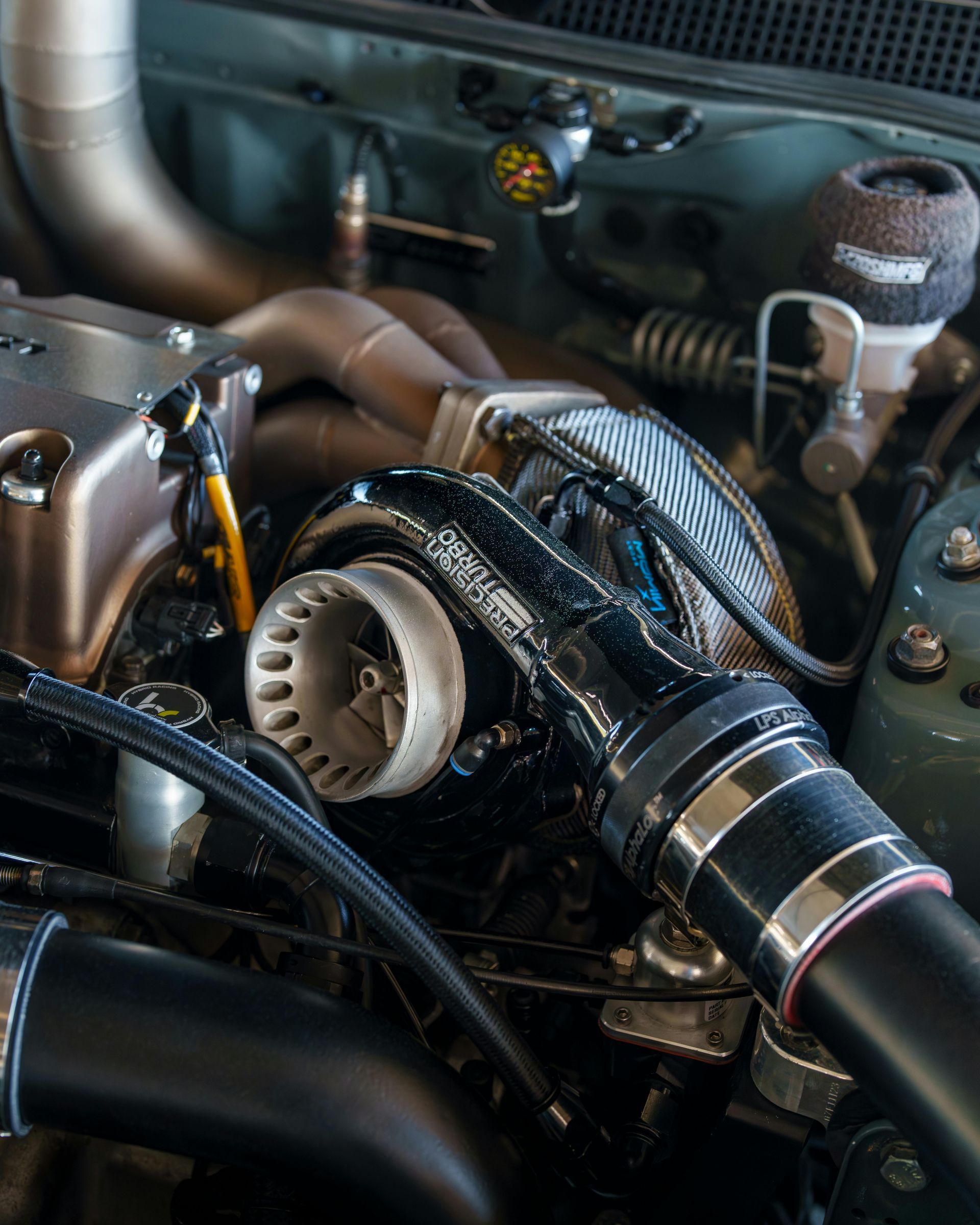 Close-up of a turbocharger engine bay with shiny piping and hoses under the hood