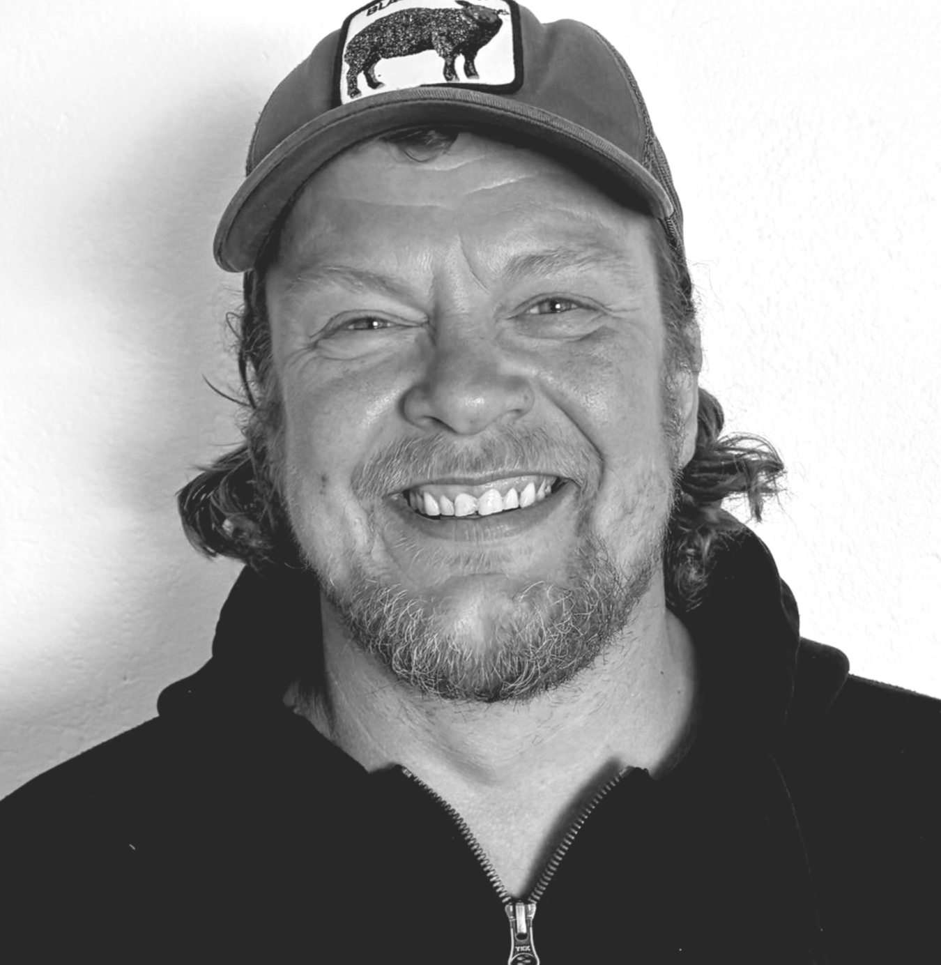 Jens har skæg smiler på et sort/hvidt foto.
