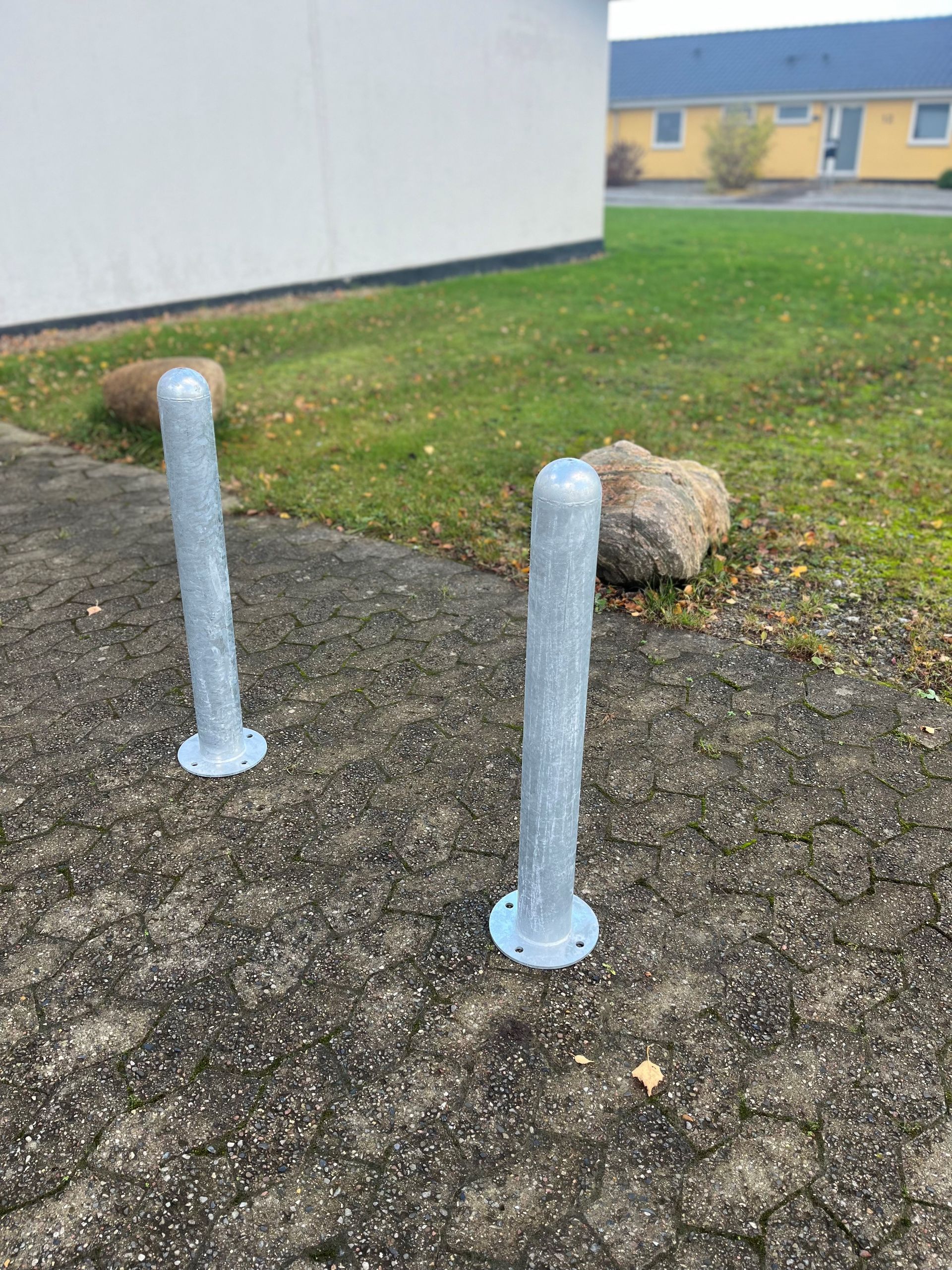 To pullerter sidder på et fortov foran et hus.