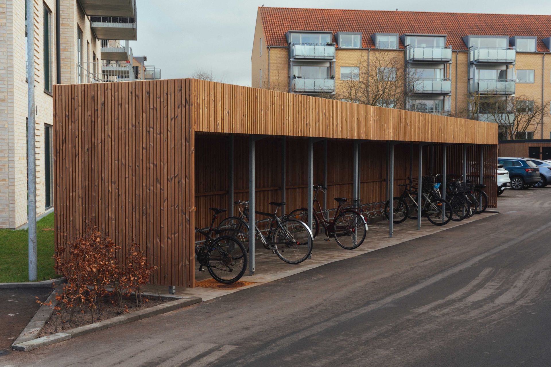 Cykelstativ omringet af træbeklædning sider og tag i et lejlighedsområde