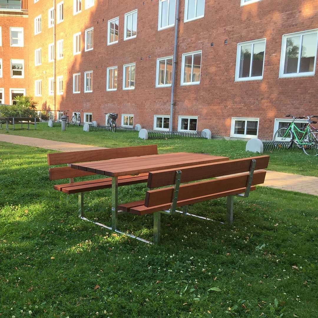 Et picnicbord med to bænke foran en murstensbygning