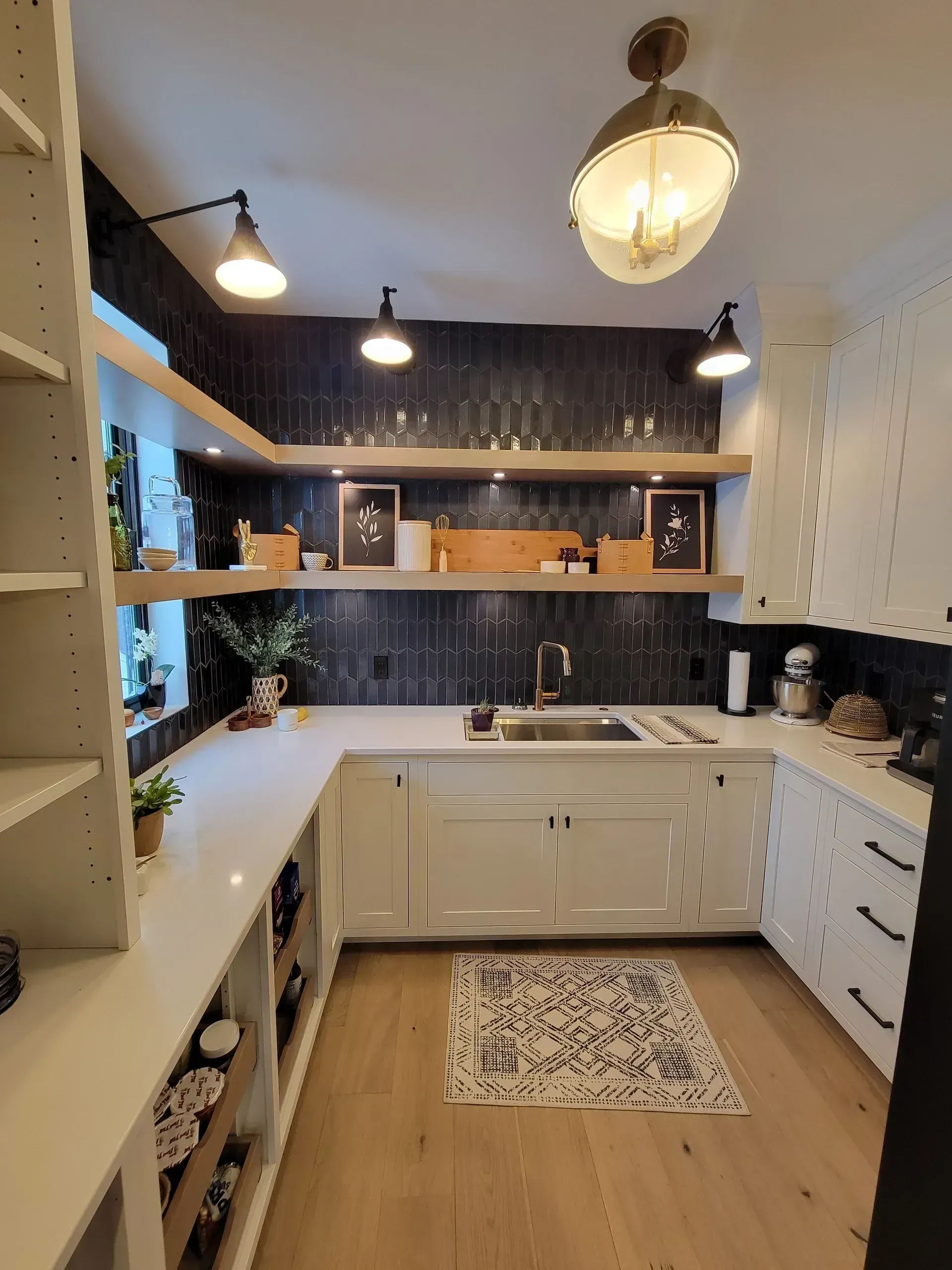 Bright kitchen with white cabinets, dark backsplash, open shelving, and a patterned rug on wood floors