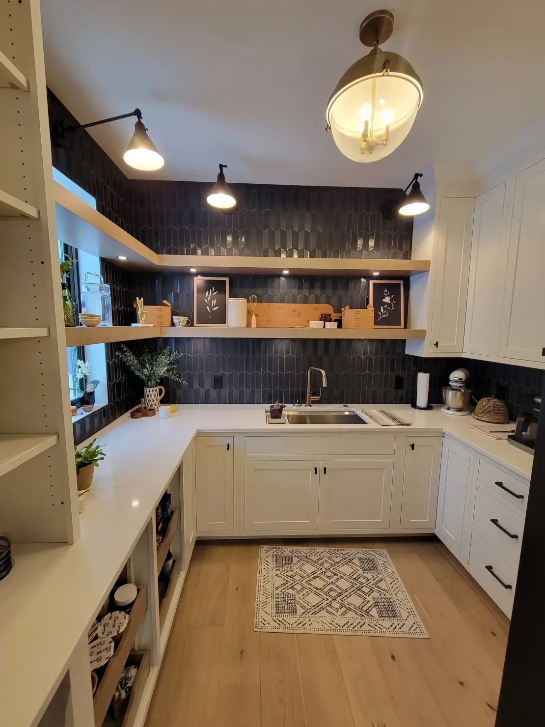 Bright kitchen with white cabinets, dark backsplash, wood floors, and open shelving.