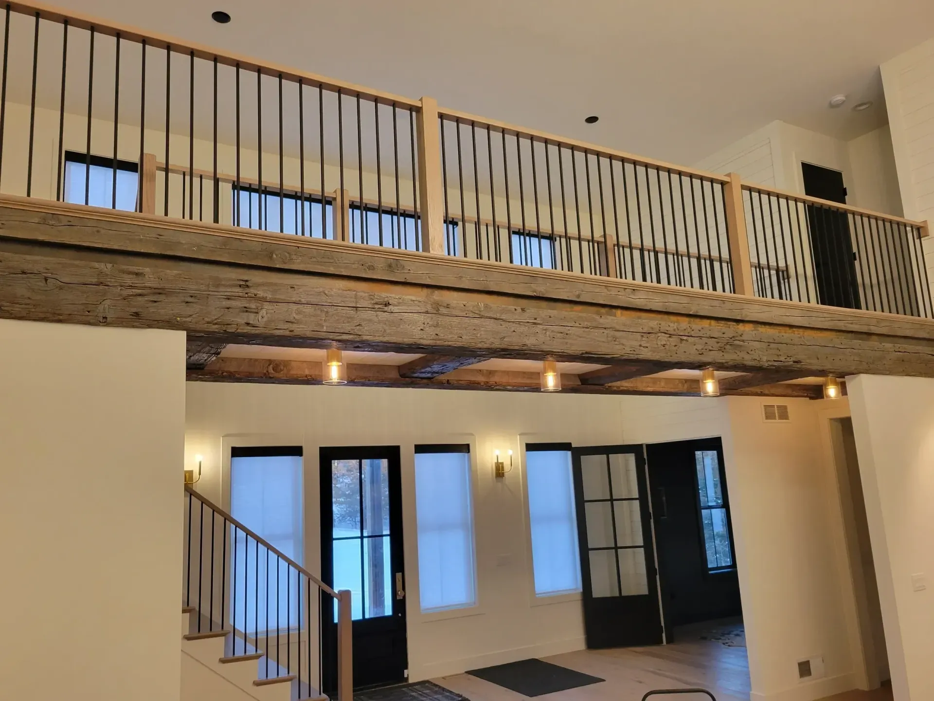 Open loft with exposed wood beam, railing balcony, and large windows in a modern room