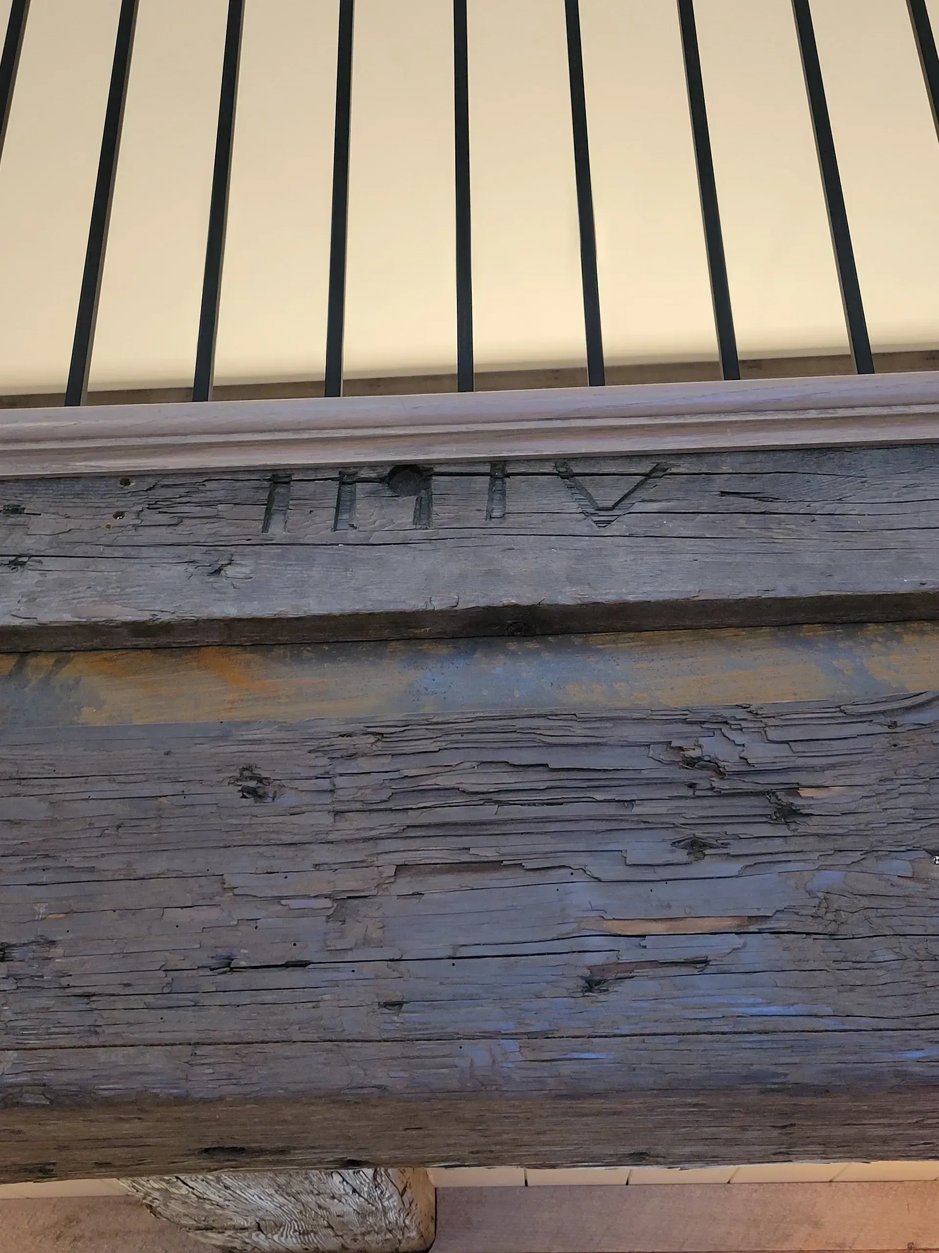 Close-up of weathered wooden boards with black metal cables above and a pale sky background