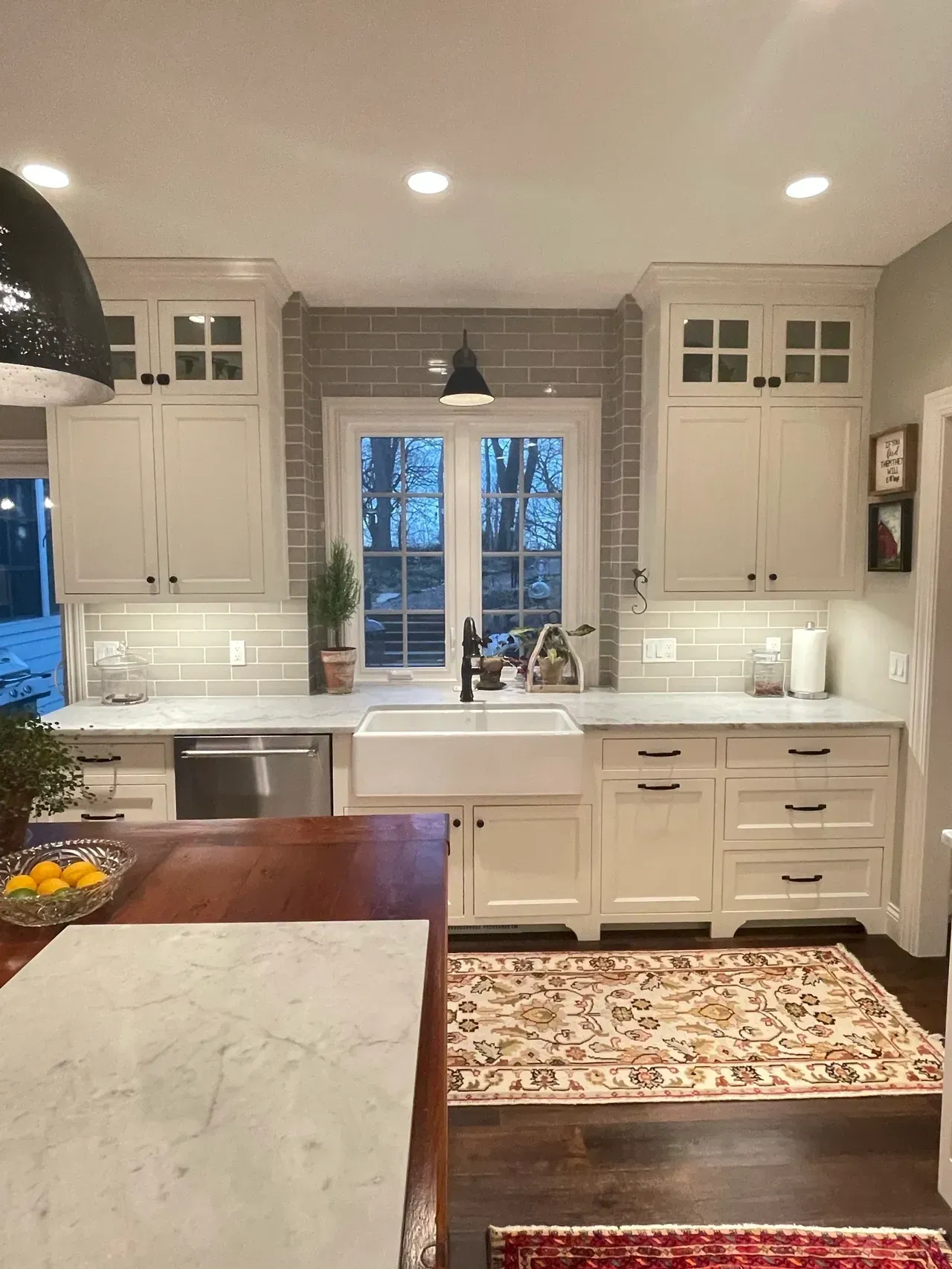 Bright white kitchen with farmhouse sink, patterned rugs, and a large island in the foreground.