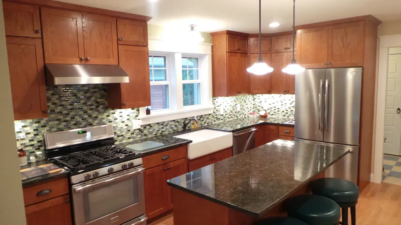 Modern kitchen with wood cabinets, granite island, stainless steel appliances, and pendant lights.