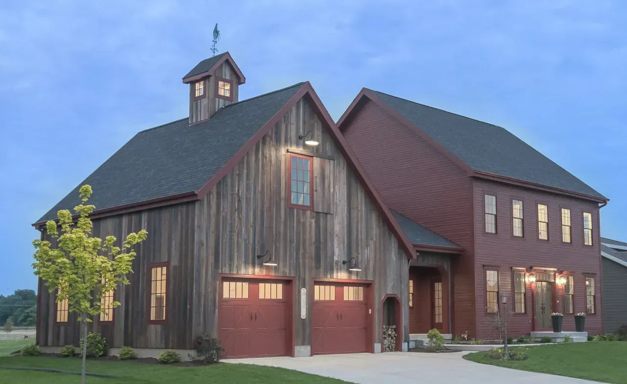 Large rustic red barn-style house with a metal roof and lit windows at dusk