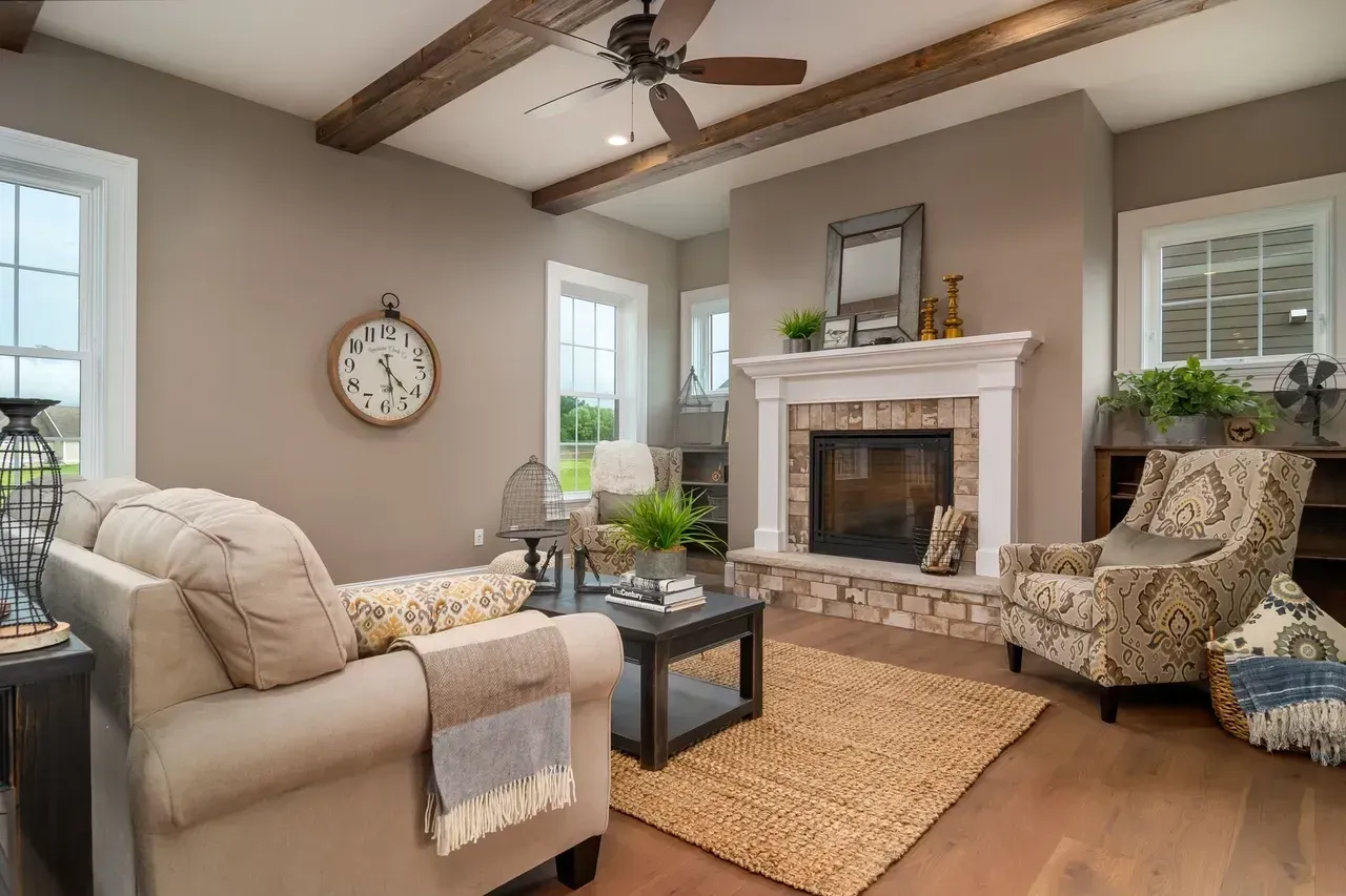 Festive living room with decorated Christmas tree, fireplace, and dark sofa under wood-beamed ceiling