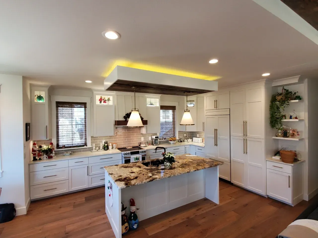 Bright modern kitchen with white cabinets, granite island, and warm wood floors