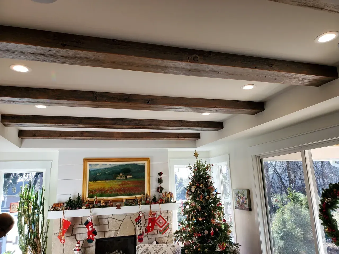 Cozy living room with Christmas tree, decorated mantel, and exposed ceiling beams