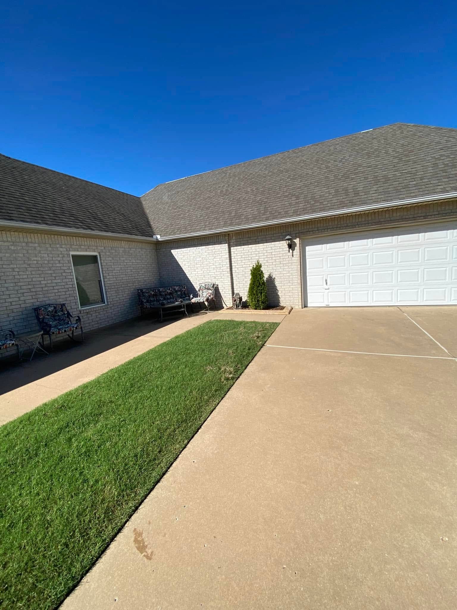 Suburban house driveway with green lawn strip, white garage, and clear blue sky