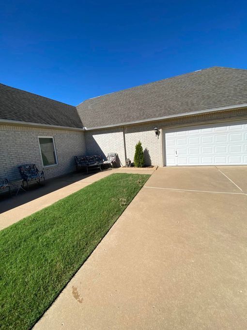 Suburban house driveway with green lawn strip, white garage, and clear blue sky