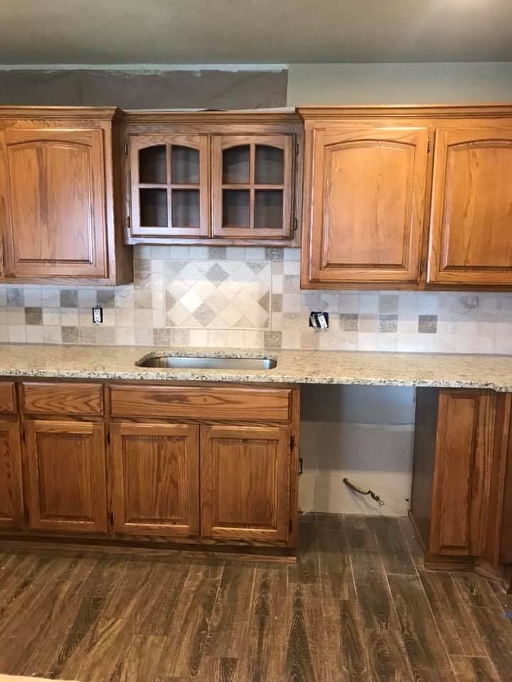 Wooden kitchen cabinets and countertop with tiled backsplash and wood-look flooring