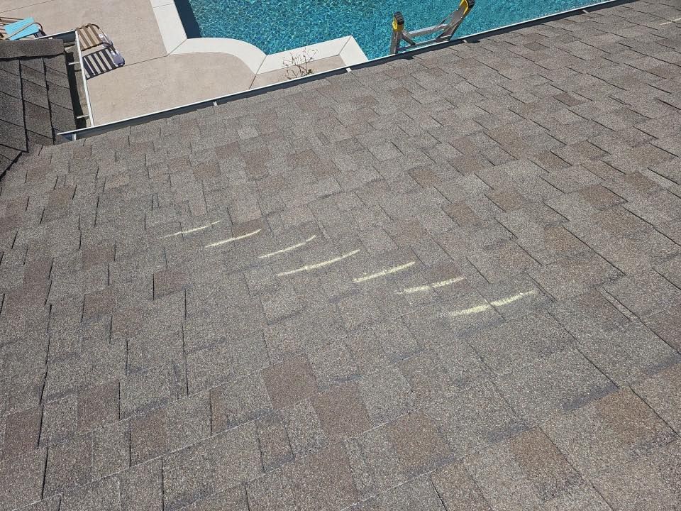 Rooftop with gray shingles beside a blue swimming pool and deck edge