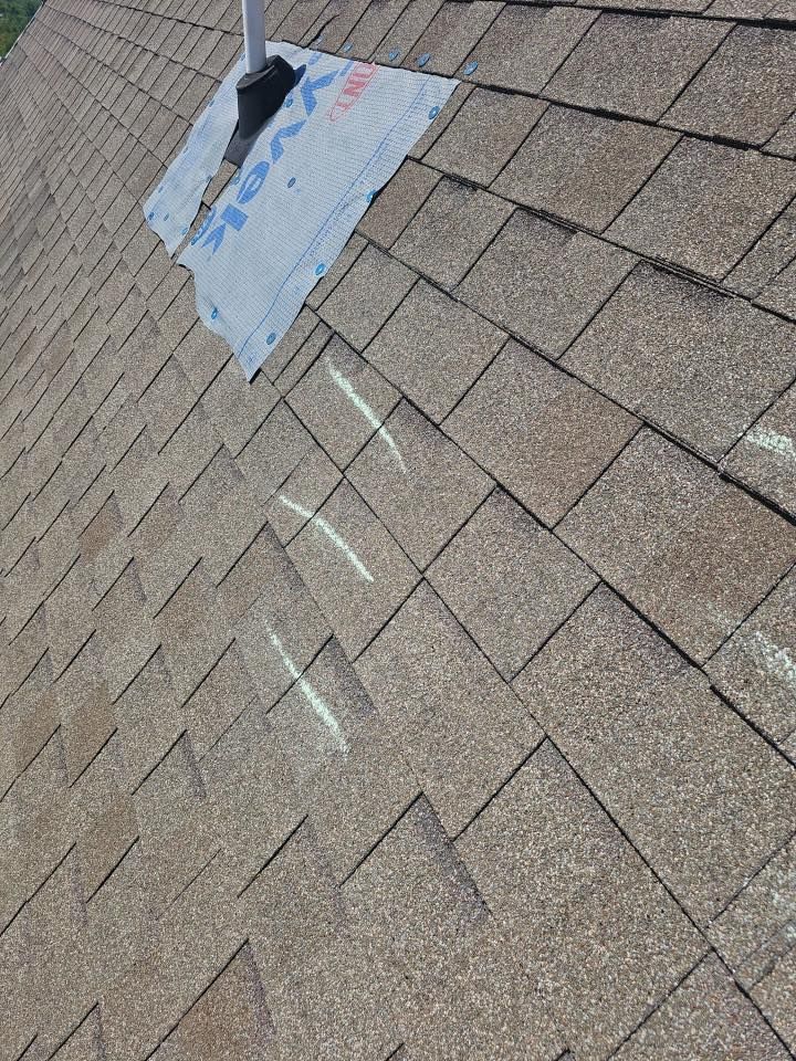 Damaged shingle roof with a tarp and visible white chalk repair marks